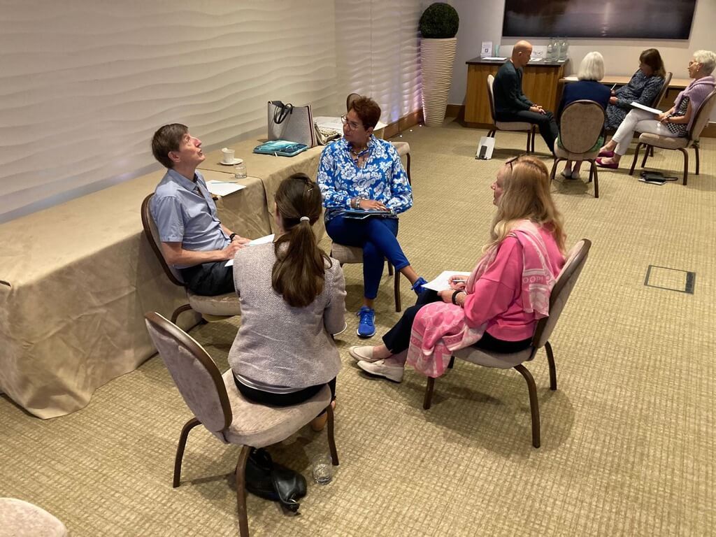 Pairs of coaches in a room having one-to-one supervision conversations.