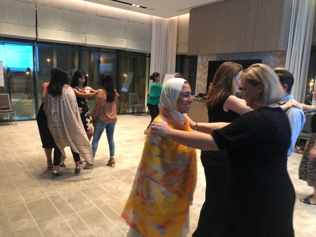 Participants engaging in interactive team building activities, dancing in pairs during a group exercise.