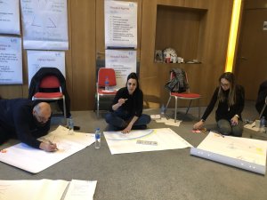 People sitting on the floor engaged in a creative journaling activity during a coaching workshop.