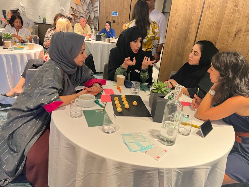 Team members in discussion around a table to share feedback and improve inclusive leadership practices