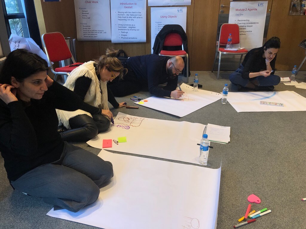 People sitting on the floor creating personal vision boards with drawings and notes.