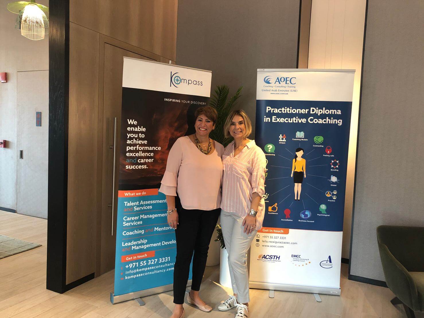 Two female leaders at a leadership coaching event with banners.
