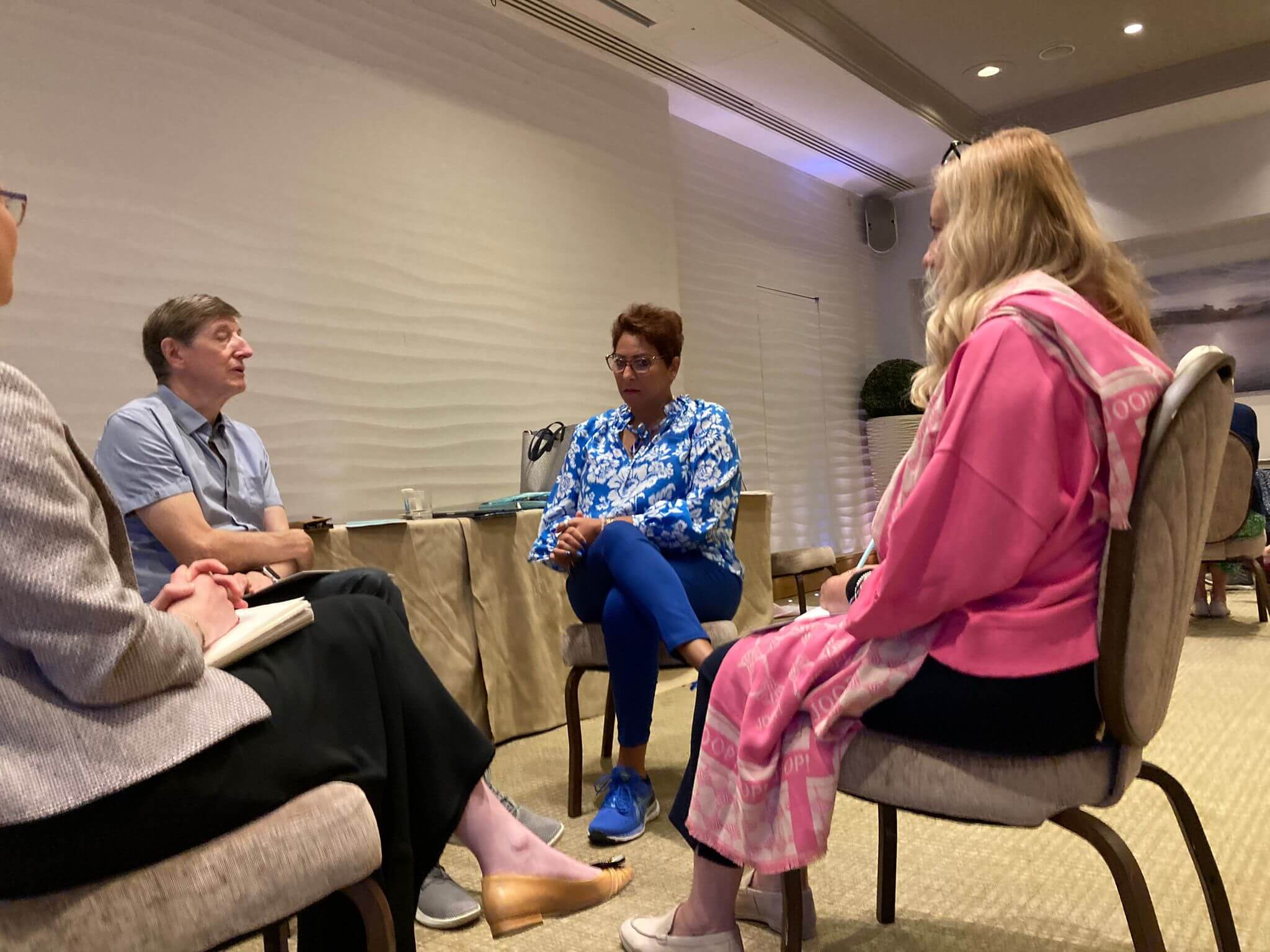 Four people seated in a circle having a focused discussion, reflecting ongoing practice in sustaining a coaching culture.