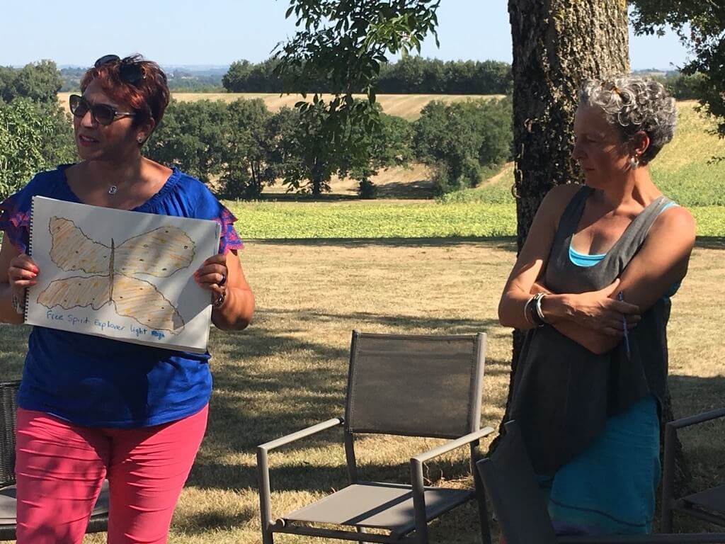 Woman presenting a butterfly drawing, reflecting how early beliefs can lead to self-sabotaging behaviours.