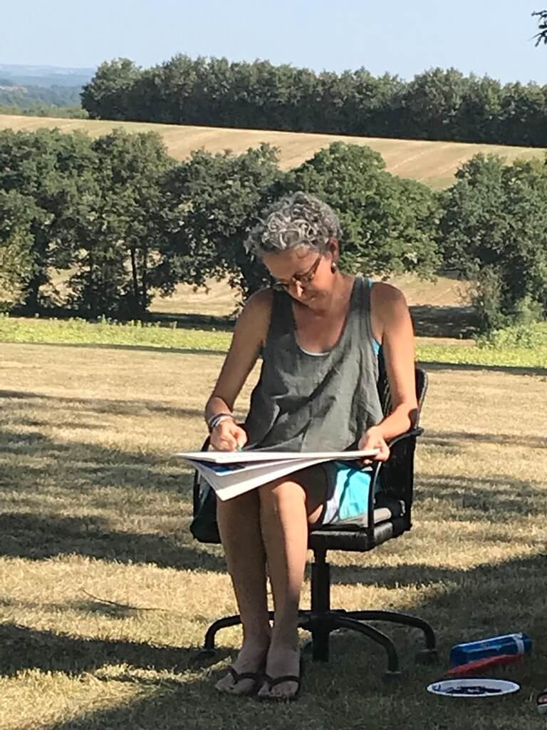 Woman sketching peacefully in nature, showing how creative activities can support self-reflection and growth.
