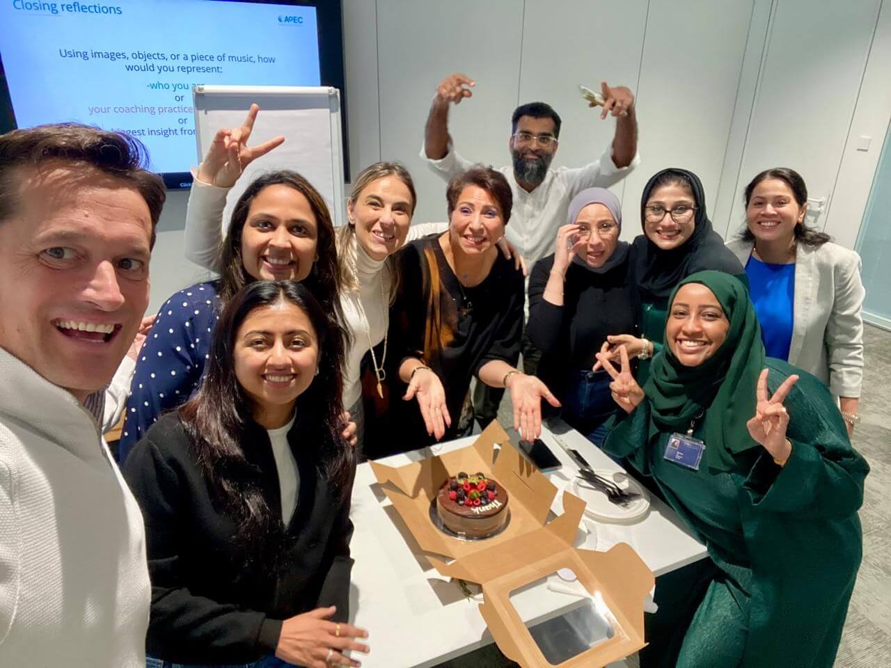 Leila Rezaiguia, a leader, celebrates with colleagues around a table, showing teamwork, emotional intelligence, and collaboration.