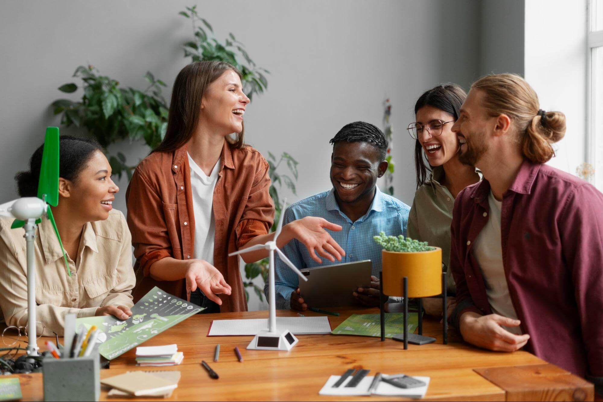 A leader guides a diverse team as they laugh and collaborate on a project, highlighting effective people management.