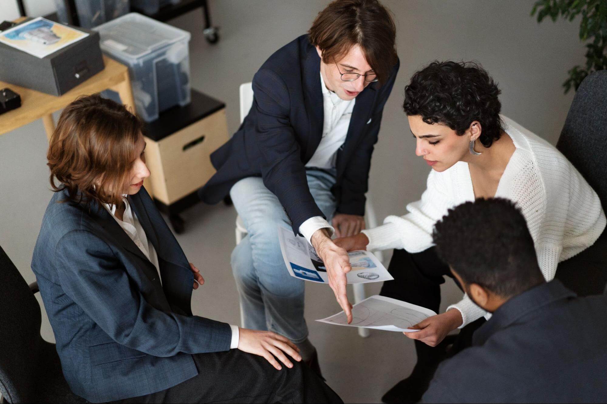 A diverse group of four professionals collaborating closely on a project, demonstrating teamwork and work ethic.