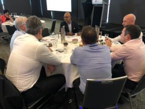 A group of people engaged in a discussion around a table, applying the GROW model for effective problem-solving.