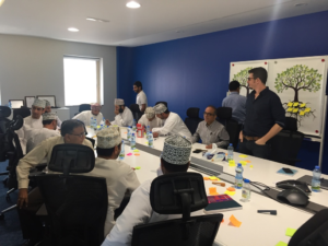 A diverse group of people around a table, actively discussing and implementing the GROW model in their conversation.