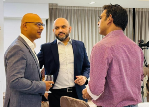 Three coaches conversing enthusiastically at a business event, exchanging ideas on the GROW model and its applications.